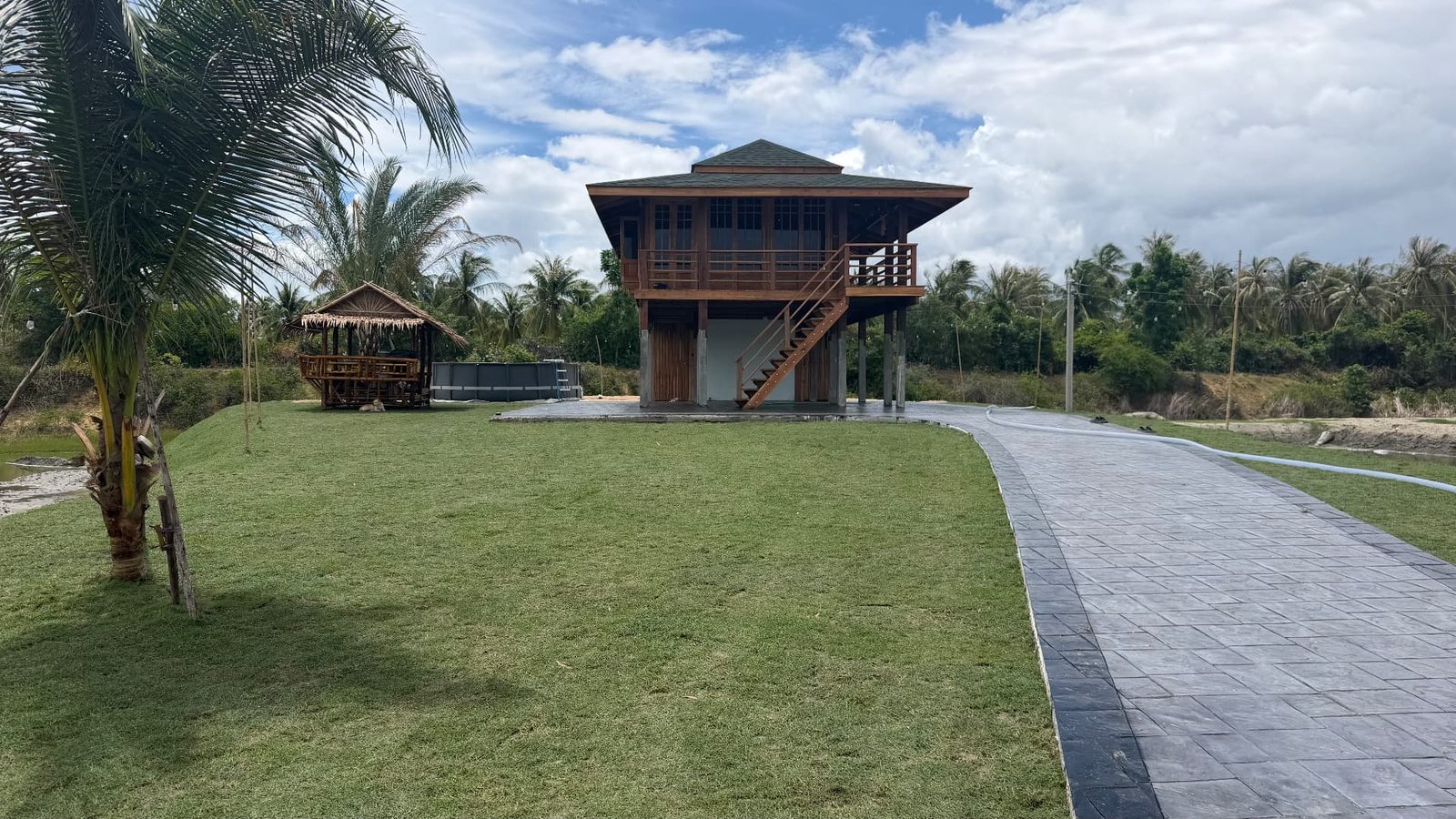 The teak villa and sala of The Nine on the lawn with coconut palms, Kui Buri